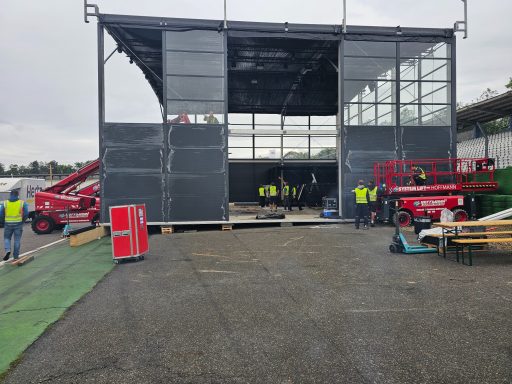 Bauprojekt: Halbfertige Struktur mit Arbeitern und Baugeräten auf einer Baustelle.